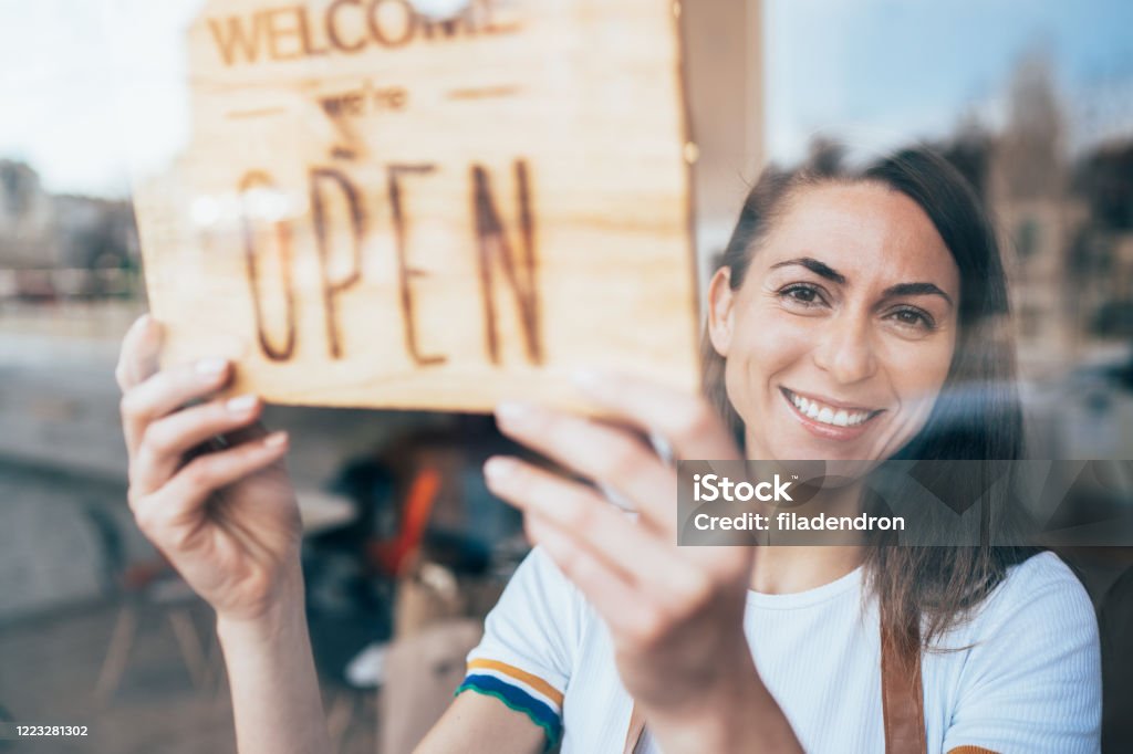 Small business Portrait of a happy business owner hanging an open sign on the door at a cafe and smiling Beginnings Stock Photo