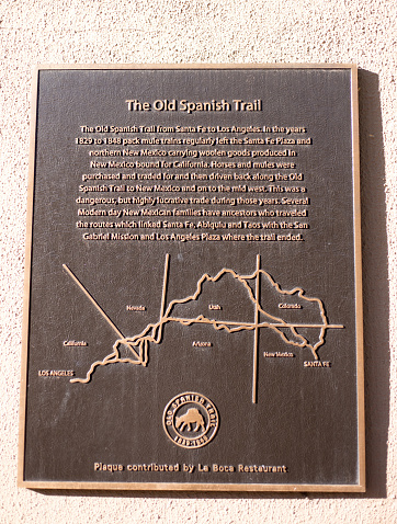 Santa Fe, NM: A historic bronze memorial plaque on an adobe wall in downtown Santa Fe explaining the “Old Spanish Trail.”