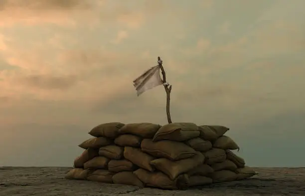 Photo of white flag behind military sand bags against sullen sky