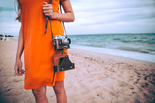 Caucasian woman with retro camera on the beach