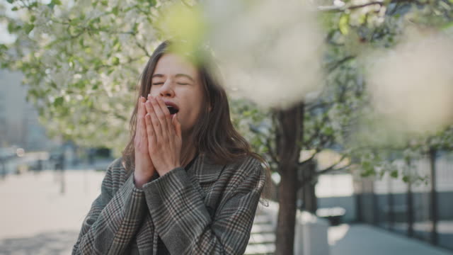 Springtime allergy. Woman sneezing on the city street