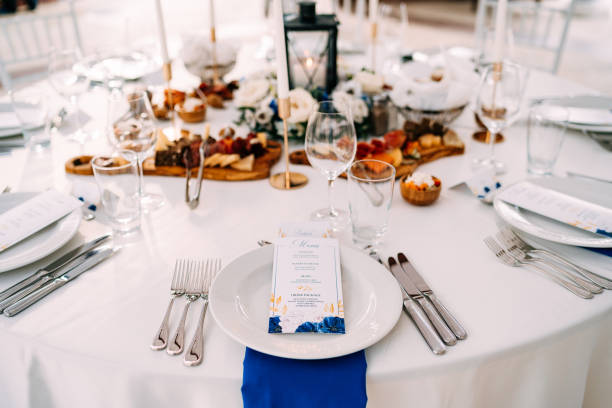 istock Wedding dinner table reception. White plate on the table, three forks on the left, three knives on the right. The wedding menu is in the plate. Top view 1223286395