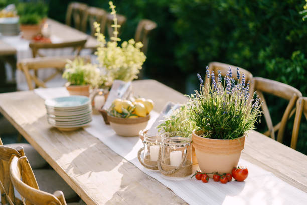 istock Wedding dinner table reception. Clay pot with flowering lavender, cherry branch tomatoes, burning candles in glass candlestick, a plate with lemons and an olive branch. A rag runner on a wooden table 1223287767