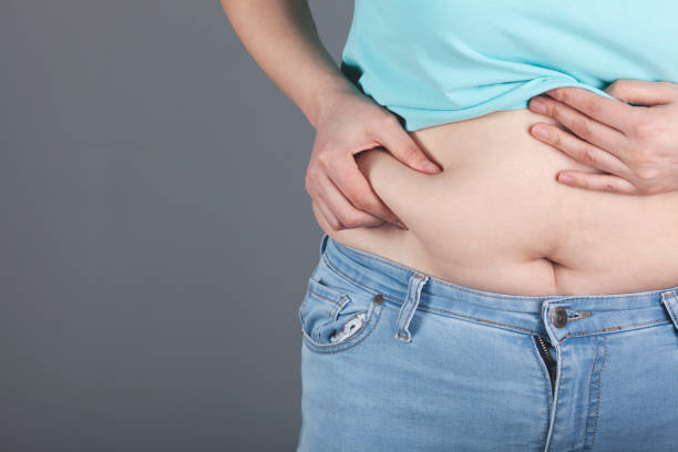 istock woman hand belly fats 1223289734