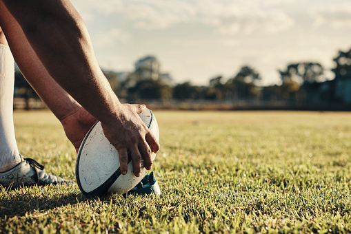 Cropped shot of an unrecognizable rugby player preparing for a kick on the field during the day