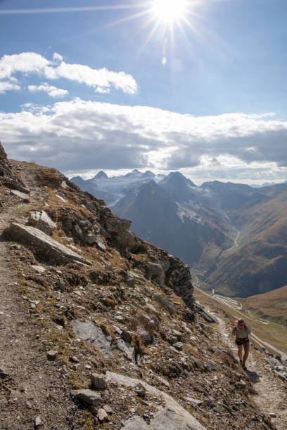 istock Female hiker walks up sunny footpath 1223300502