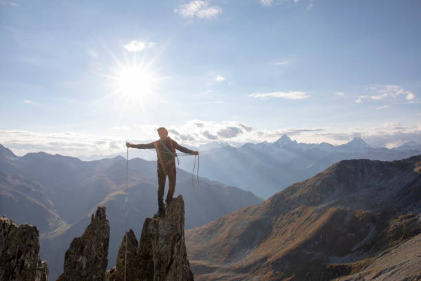 mountaineer climbs up rock pinnacle at sunset - people strength leadership remote imagens e fotografias de stock