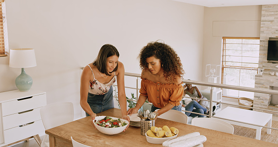 Shot of two young women laying a table in preparation for a lunch party