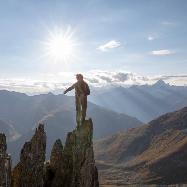 mountaineer climbs up rock pinnacle at sunset - people strength leadership remote imagens e fotografias de stock