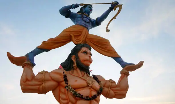 View of idol Hanuman holding Hindu Gopd Rama with bow and arrows, against blue sky