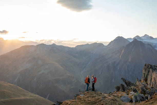 istock Female hikers relax on mountain ridge at sunset 1223305869