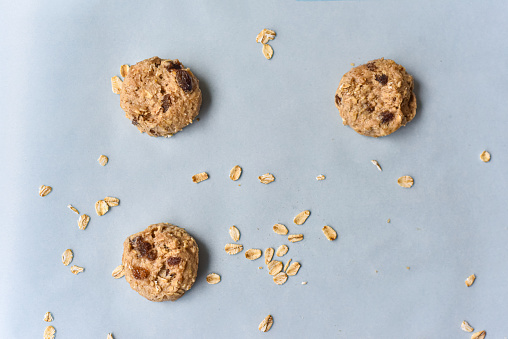 A group of uncooked oatmeal raisin cookies on a parchment sheet