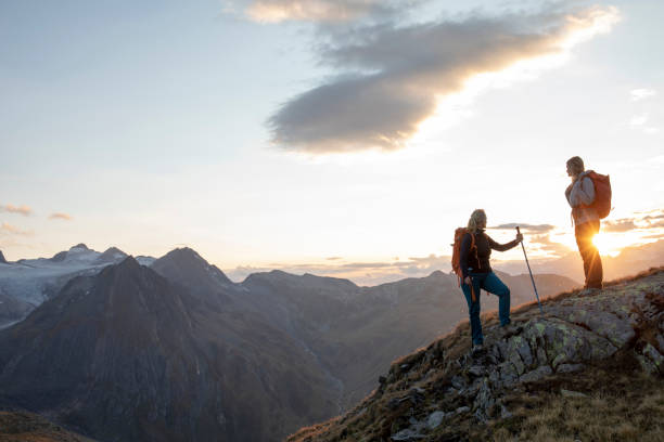 istock Female hikers relax on mountain ridge at sunset 1223307380