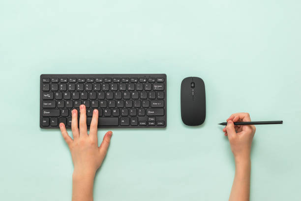 istock Hands with black keyboard, mouse and pencil on a light background. 1223313875