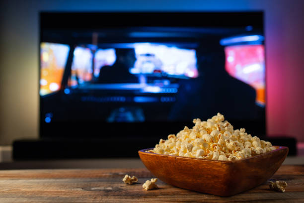 tv가 작동하는 배경에 팝콘과 리모컨의 나무 그릇. 집에서 영화 또는 tv 시리즈를 보는 저녁 아늑한 - popcorn snack bowl isolated 뉴스 사진 이미지