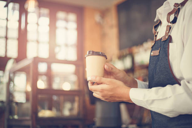 Male Barista preparing coffee for customer in coffee shop. Cafe owner serving a client at the coffee shop. stock photo