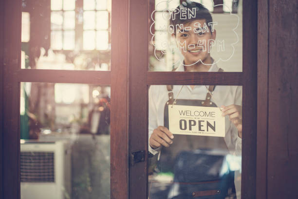 Store owner turning open sign broad through the door glass and ready to service. stock photo