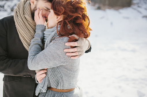 Stylish young beautiful couple embracing. Background winter mountains and forest