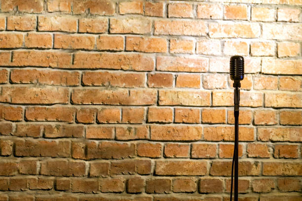 Microphone ready on stage against a brick wall Microphone ready on stage against a brick wall comedian stock pictures, royalty-free photos & images