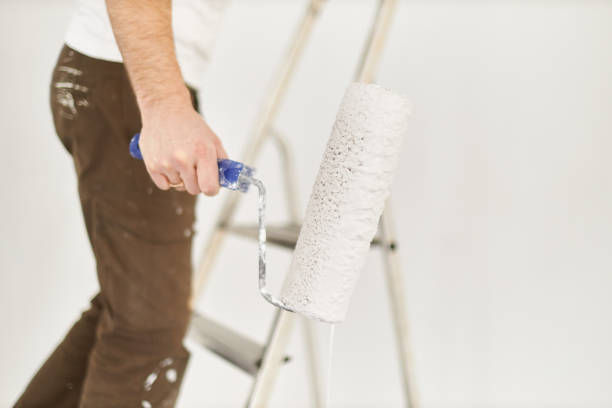 istock A middle-aged man paints paint on a wall in his house using a paint roller, paint bucket, paint and a ladder 1223324681