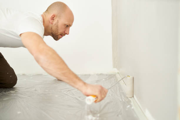 istock A middle-aged man paints paint on a wall in his house using a paint roller, paint bucket, paint and a ladder 1223324822