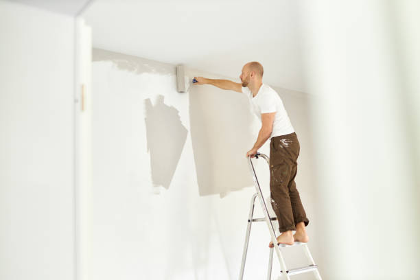 istock A middle-aged man paints paint on a wall in his house using a paint roller, paint bucket, paint and a ladder 1223324824