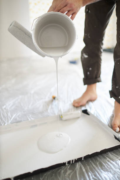 istock A middle-aged man paints paint on a wall in his house using a paint roller, paint bucket, paint and a ladder 1223324863