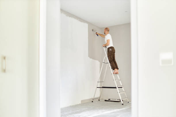 istock A middle-aged man paints paint on a wall in his house using a paint roller, paint bucket, paint and a ladder 1223325010