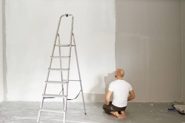 istock A middle-aged man paints paint on a wall in his house using a paint roller, paint bucket, paint and a ladder 1223326161