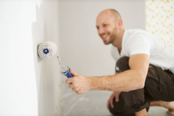 istock A middle-aged man paints paint on a wall in his house using a paint roller, paint bucket, paint and a ladder 1223326216