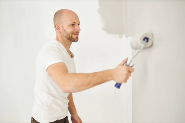 istock A middle-aged man paints paint on a wall in his house using a paint roller, paint bucket, paint and a ladder 1223326586