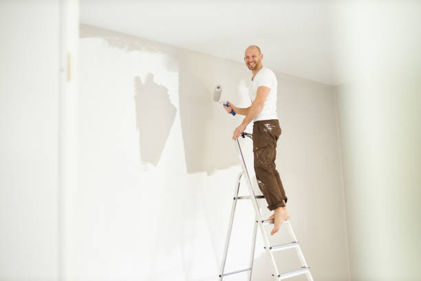 istock A middle-aged man paints paint on a wall in his house using a paint roller, paint bucket, paint and a ladder 1223326896