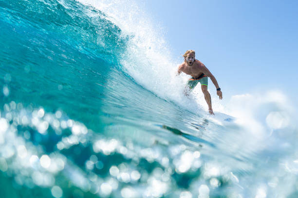 長い髪を持つ若い男のサーファーは、モルディブで速く、完璧な海の波をサーフィン - splashing maldives human hair spray ストックフォトと画像