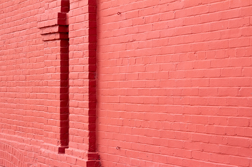 This image shows an old traditional brick wall texture background, painted with a sherbet red color, and showing brickwork moulding columns.