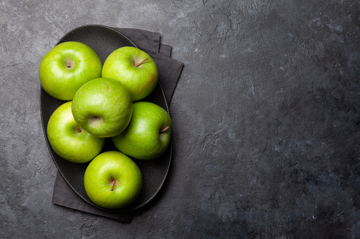 Ripe green apple fruits on dark stone table. Top view with copy space. Flat lay