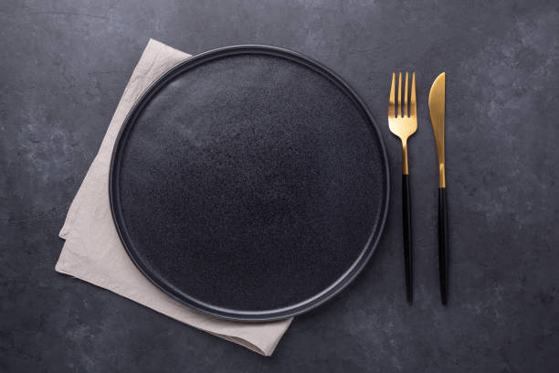 istock Empty ceramic plate and cutlery on dark stone background Copy space Top view 1223334555