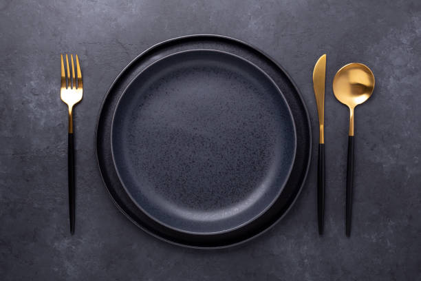 Dark table setting. Two empty ceramic plates and cutlery on stone background Copy space for your text Dark table setting. Two empty ceramic plates and cutlery on stone background Copy space for your text - Image restaurant table layout stock pictures, royalty-free photos & images