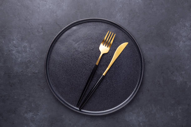 istock Empty ceramic plate and cutlery on dark stone background Copy space Top view 1223334586