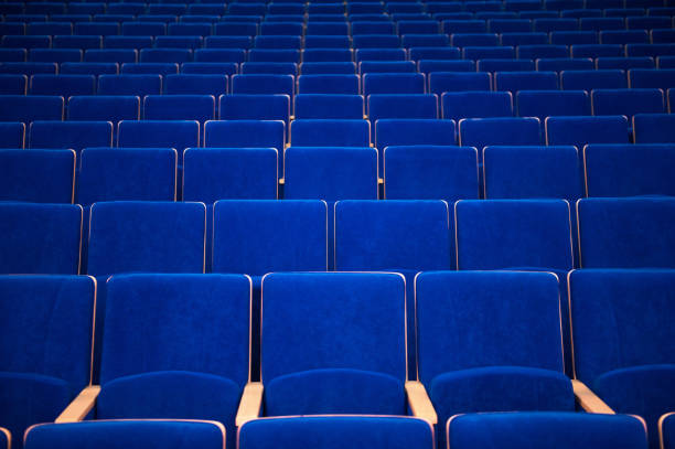 Rows of empty golden orange cushions theatre seats viewed from the side creating a repeating pattern