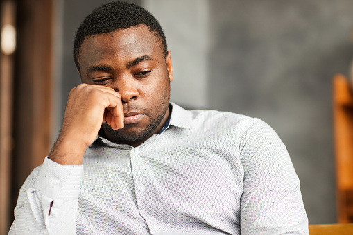 African young man sitting with sad look or thinking about something