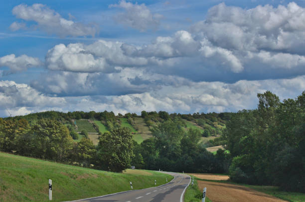 istock A road running towards a hills with fields and trees 1223340390