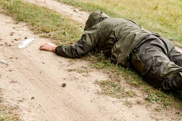 istock a creeping man on a field road reaches for a bottle 1223340556
