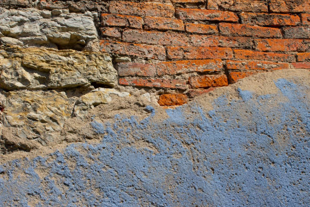Old and weatherd natural stone and brick wall with light blue paint plaster fallen off on on one side for background