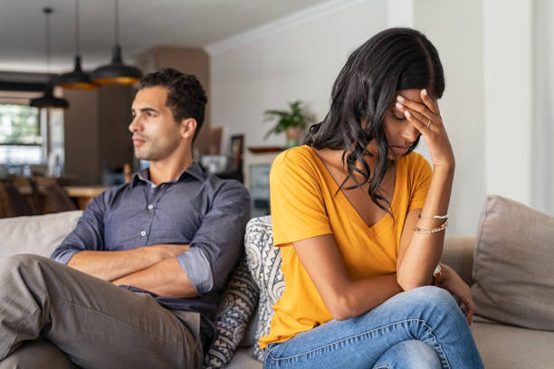 Young couple having argument at home Middle eastern young couple sitting on couch after a fight. Sad indian woman sitting with hand on head after quarrel with boyfriend at home. Angry latin couple ignoring each other on the sofa, having relationship troubles. relationship breakup photos stock pictures, royalty-free photos & images