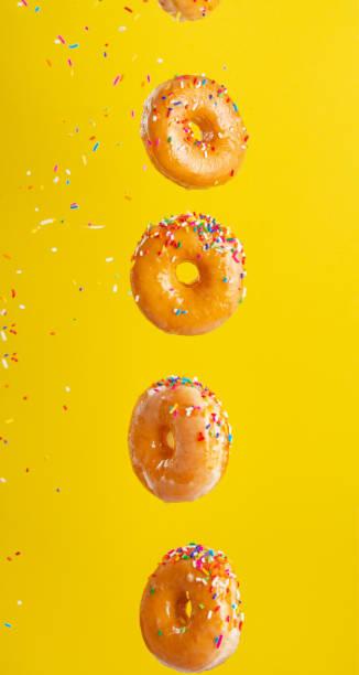 istock Various decorated donuts in motion falling on a yellow background. Sweet and iced donuts fall or fly in motion. With caramel. Yellow background, vertical photo. 1223344178