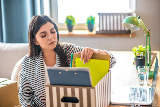 istock Young woman in a striped jacket packing documents and looking involved 1223345902