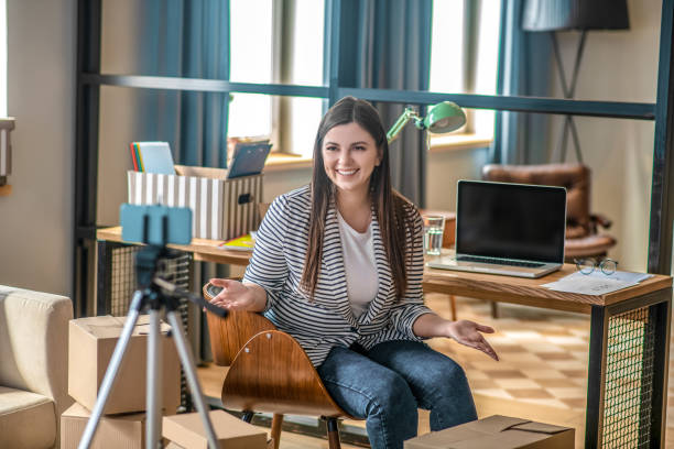 istock Dark-haired pretty young woman smiling while having a video conference 1223346011