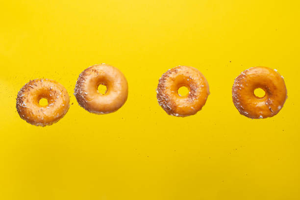 istock Various decorated donuts in motion falling on a yellow background. Sweet and iced donuts. With pieces of chocolate. Horizontal. Light and tender photo. 1223346943