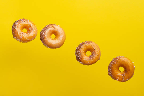 istock Various decorated donuts in motion falling on a yellow background. Sweet and iced donuts. With pieces of chocolate. Horizontal. Light and tender photo. 1223347420