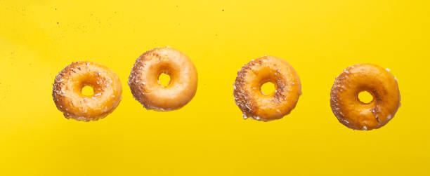 istock Various decorated donuts in motion falling on a yellow background. Sweet and iced donuts. With pieces of chocolate. Horizontal. Light and tender photo. 1223347510